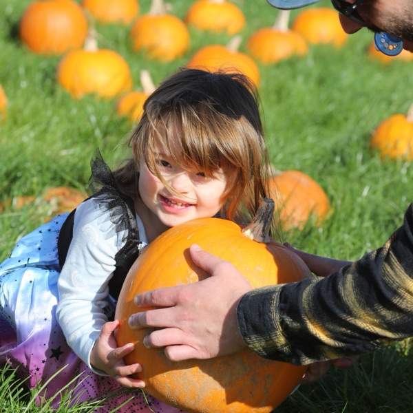 A child hugging a pumpkin in the patch